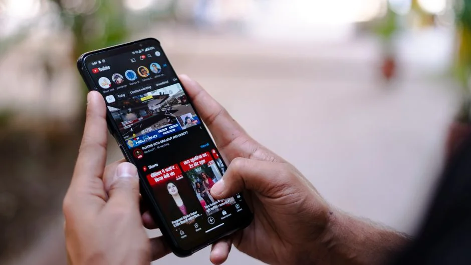 Person using smartphone for stock market analysis at home office.
